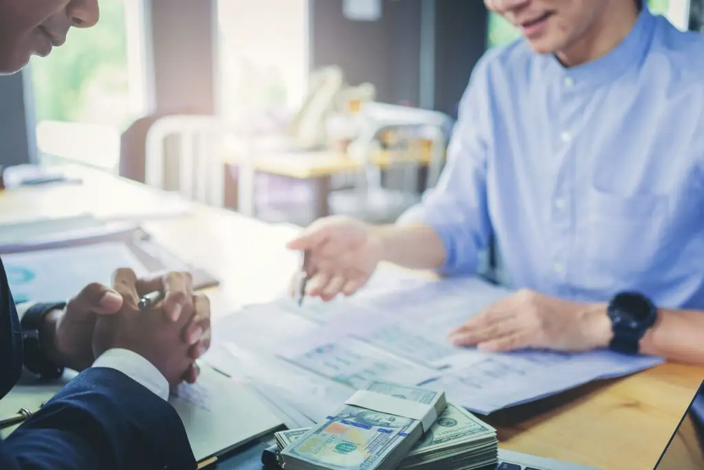 Two men going over paperwork next to money