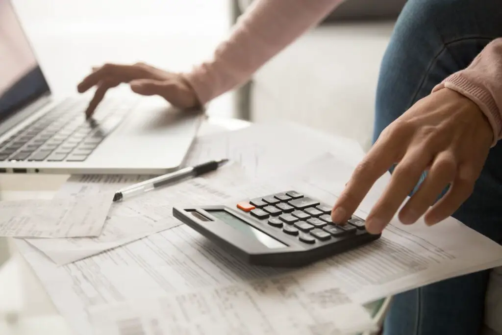 A woman using a calculator and a laptop