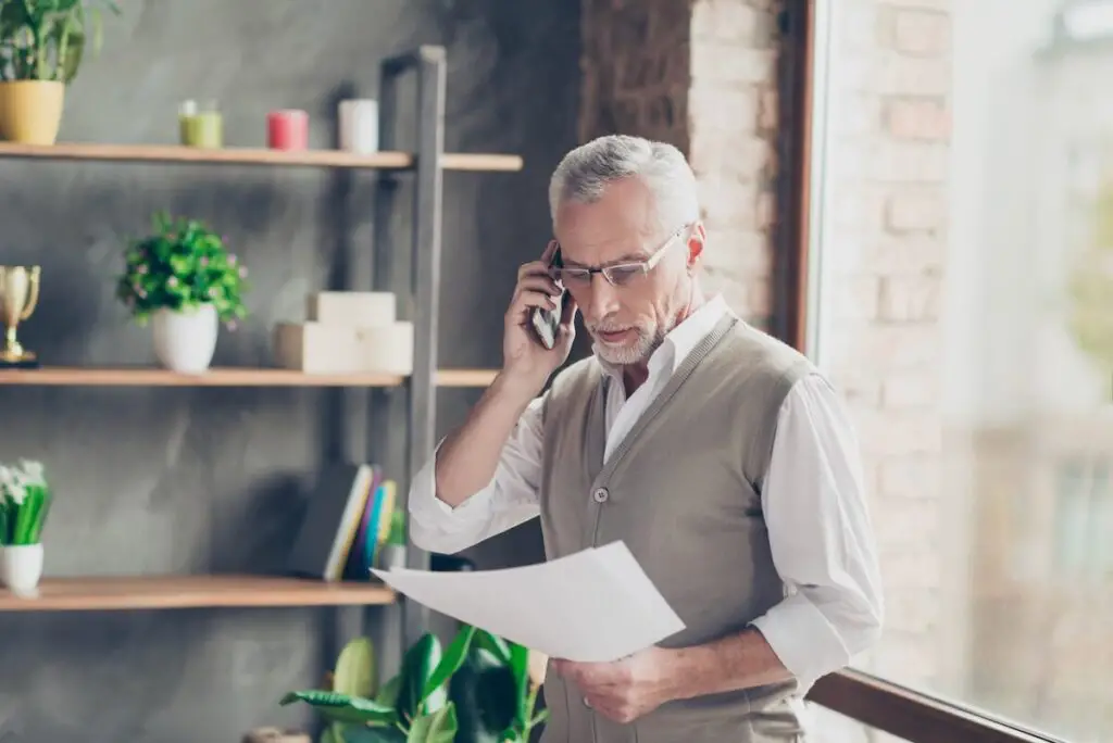 A man talking on the phone while looking at papers