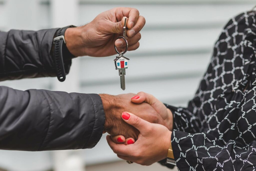 A man and a woman shaking hands with the man handing over keys