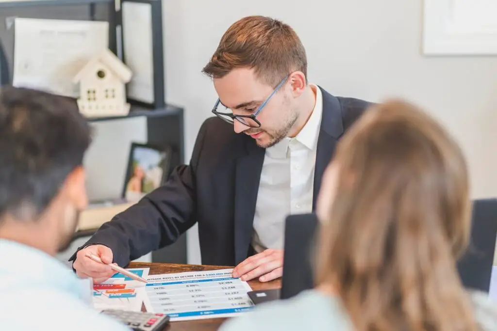 Man sitting at a table and showing customers information on the paper