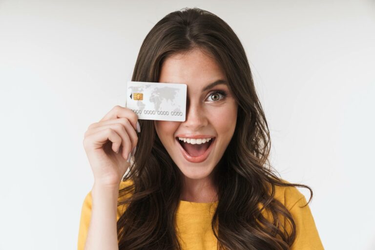 A smiling woman holding a silver credit card