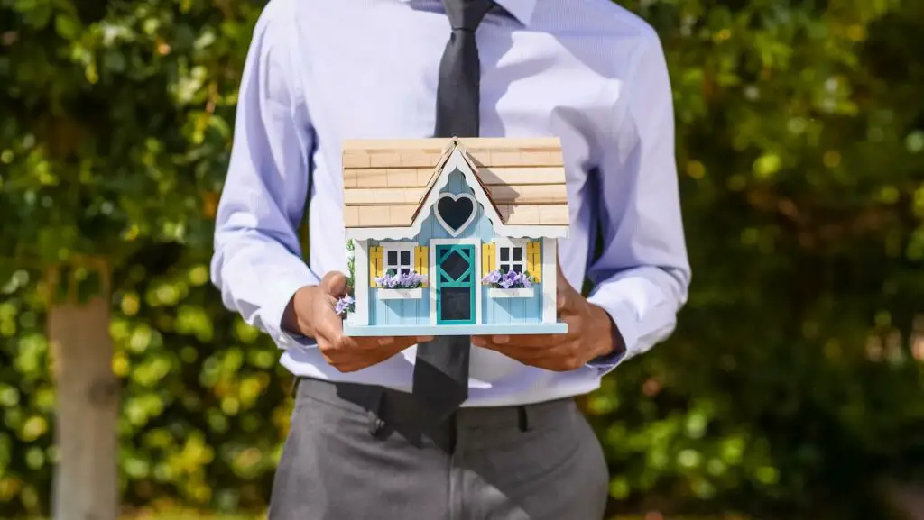 A person holding a miniature toy house 