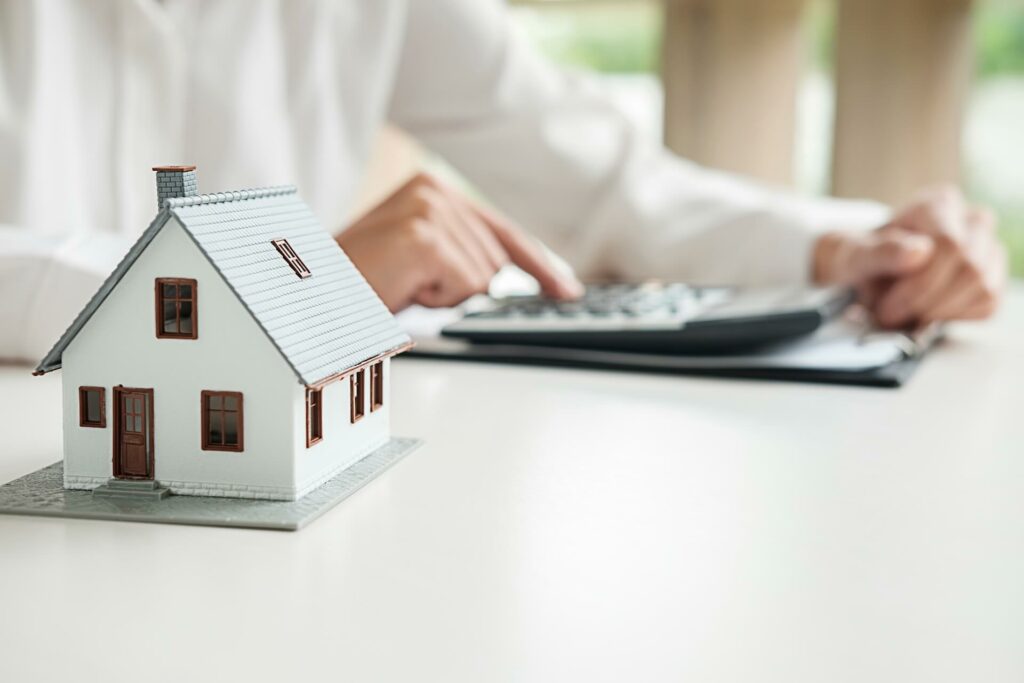 A person using a calculator next to a house model