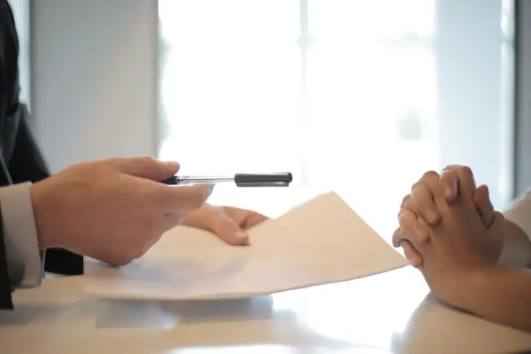 A person passing paper and pen to another person