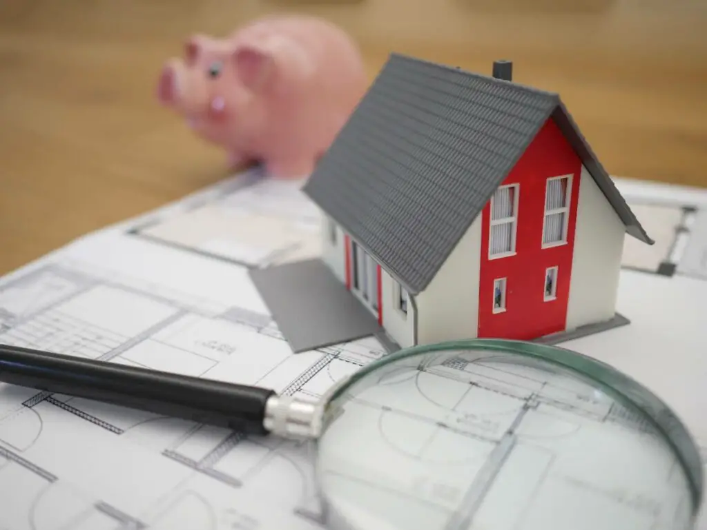 House blueprints, a small house model, and a magnifying glass
