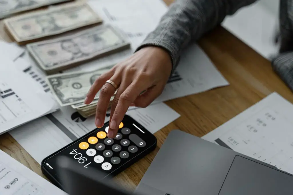  A woman using a calculator beside a pile of cash