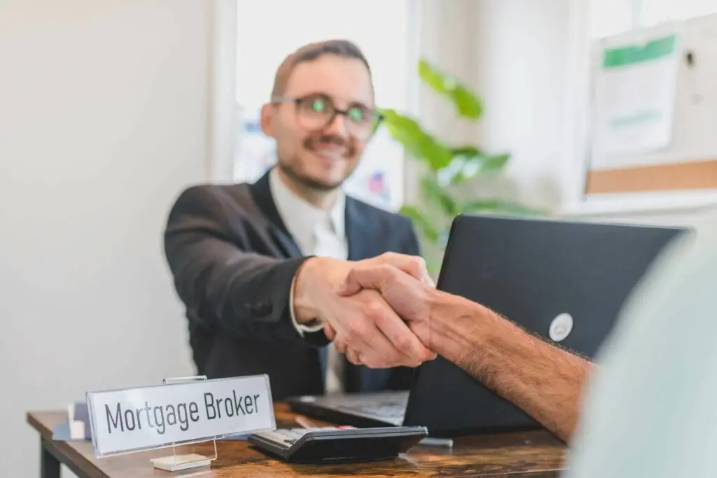 A mortgage broker smiling and shaking hands with a client