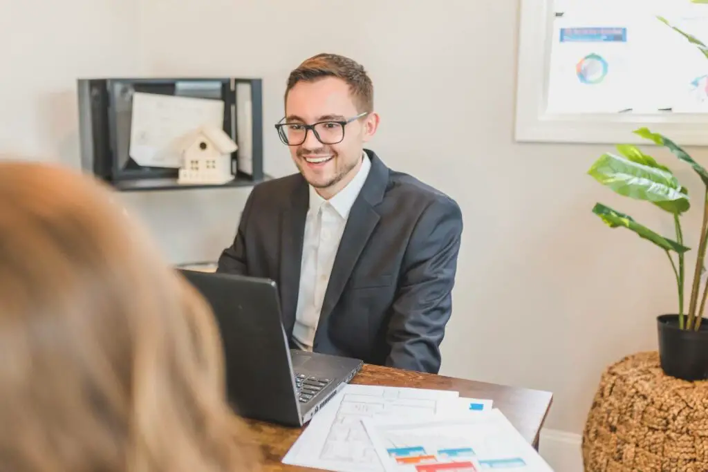 A broker smiling while talking to a person in his office 