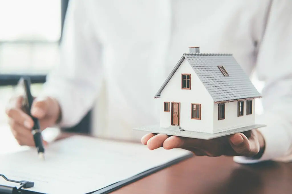  A person holding a small model of a house in their hand