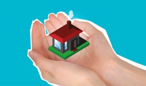 A person holding a cartoon model of a house