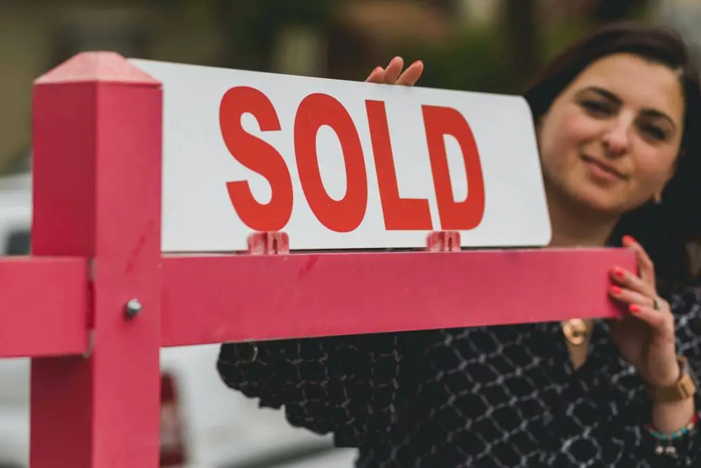  A real estate agent holding a "sold" sign 