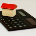 A small toy in the shape of a house on a calculator
