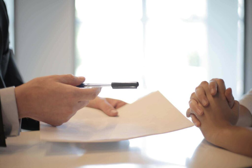 A person giving a paper to sign to another person
