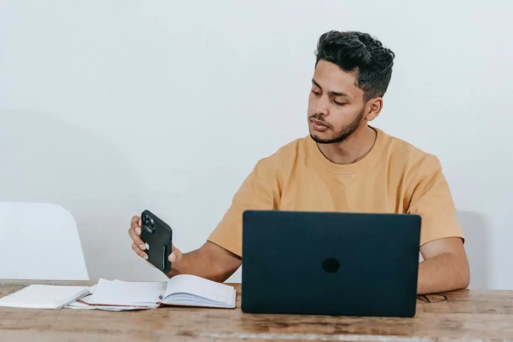 A man using a smartphone and laptop for work