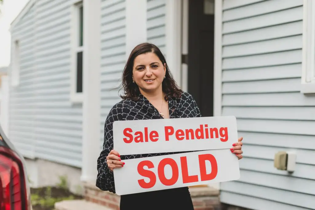 Woman holding sold sign 